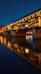 Ponte Vecchio at night. Magically illuminated bridge under starry sky.