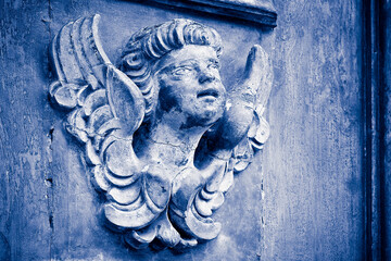 Sculpture of an old wooden angel against a wooden door of a church - more than 100 years old