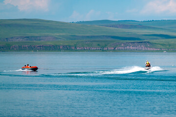 Fototapeta premium A man in a life jacket floats on a scooter on a lake.