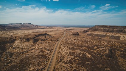 An aerial view of a highway running alongside an expansive rocky terrain.