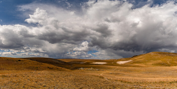 The shared Continental Divide and Colorado Trail snakes its way across the tundra expanse of Snow Mesa as storm clouds form above in this scenic panorama.