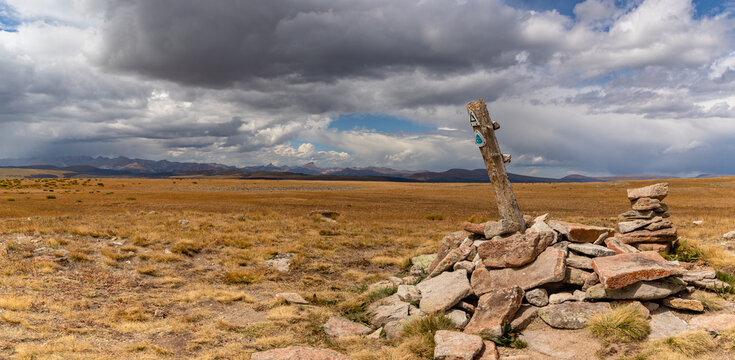 Panorama of a shared Continental Divide and Colorado Trail marker atop Snow Mesa in the San Juan Mountains near Lake City Colorado.