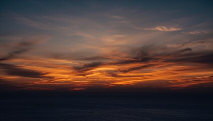 Obraz premium Twilight Clouds Above Ocean at Dusk, Vibrant Orange Sunset with Moody Blue Sky and Golden Hour Glow on Summer Evening Landscape