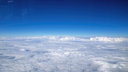 Stunning sky panorama featuring fluffy white clouds and ample space for text or ads. Aerial view from an aircraft window showcasing serene cloud formations. The theme of flying and aviation.