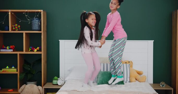 Sisters, bedroom and laughing with jumping in pyjamas for fun with sleepover for child development in house. Siblings, cheerful and active or energetic with happiness on weekend for love with family.