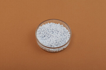 Virgin polyethylene terephthalate or PET homopolymer granules in Petri dish. Granulated plastic polymer for production of plastic utensils and other products.
