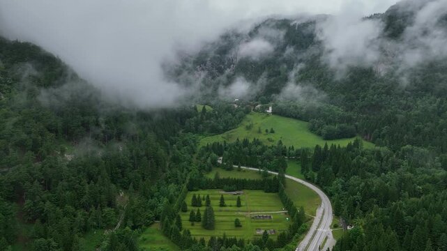 Drone aerial footage flying over alpine road in Slovenia Alps, during cloudy summer day with scenic peaceful mountains forest and natural calm atmosphere of travel