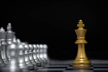 Golden king chess piece standing alone facing full silver chess army, symbolizing leadership, strategy, courage, risk, power dynamics, business challenge, and bold decision making.