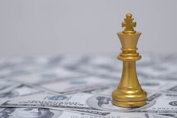 Golden king chess piece standing on US dollar bills symbolizes leadership, wealth, financial power, and strategic success in business. Ideal for finance, investment, and corporate themes.