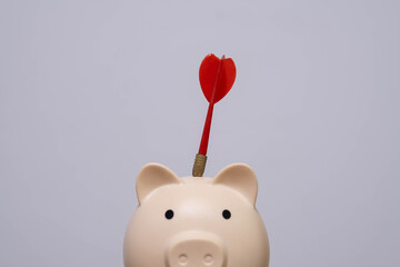 Piggy bank with red dart hitting the top, representing financial goals, smart saving strategy, investment targeting, money planning, and successful budgeting concept.