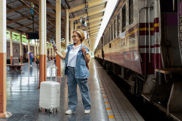 Fototapeta premium Happy Asian senior boarding a train at the station