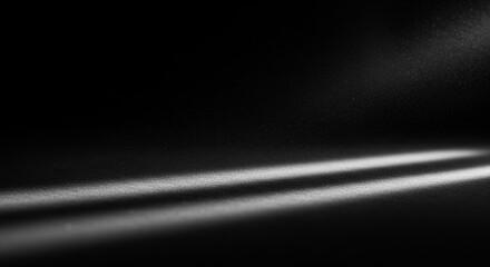 Monochrome abstract background with light rays shining on a dark surface