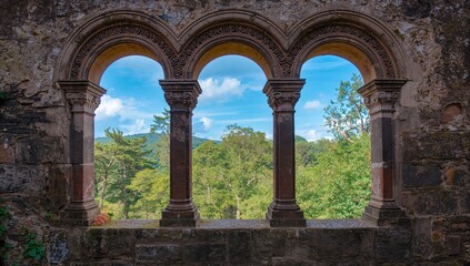 Obraz premium Looking through a historic stone window at lush greenery and the sky