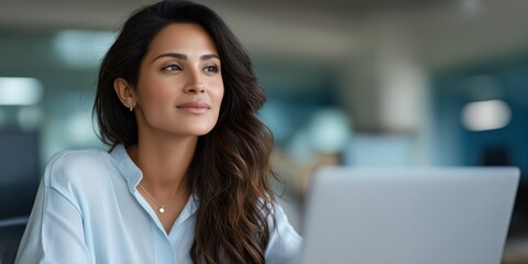 Confident young hispanic woman working on laptop in modern office setting