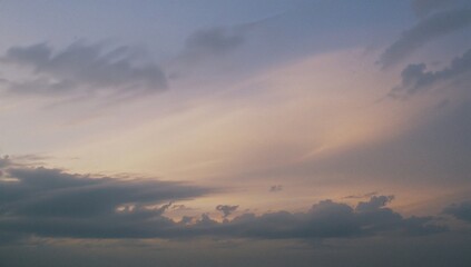 Obraz premium A serene sunset paints the sky with delicate pastel hues, as clouds softly shade a peaceful scene below.