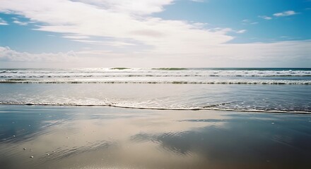 Fototapeta premium Serene Ocean Waves Gently Kissing the Sandy Shore Under a Vast Blue Sky.