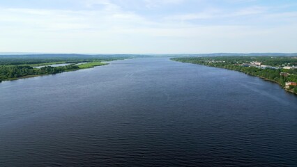 Wide river flows through green landscape under blue sky. Clip