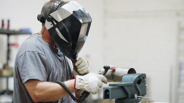Professional welder using tig welder on metal pipe