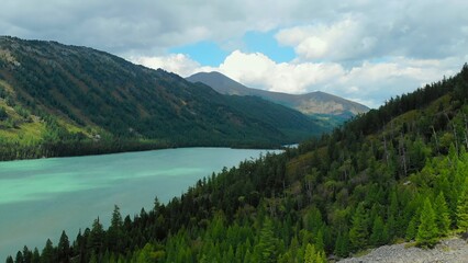 Aerial view of alpine turquoise lake and forested mountains. Media