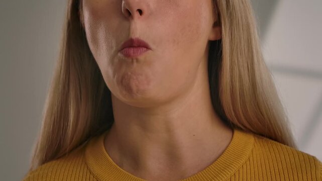 Close up of a woman eating a crunchy potato chip, highlighting the texture and the act of eating with delight. Slow motion.