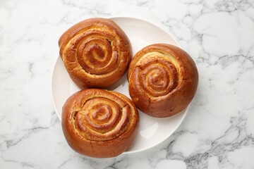 Fototapeta premium Tasty roll buns on white marble table, top view