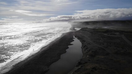 Fototapeta premium Fog rolling over black sand beach and river estuary