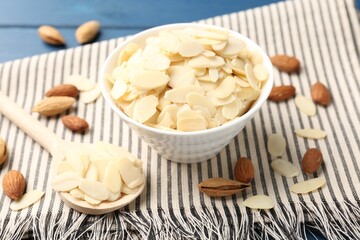 Fresh almond flakes and whole nuts on table, closeup