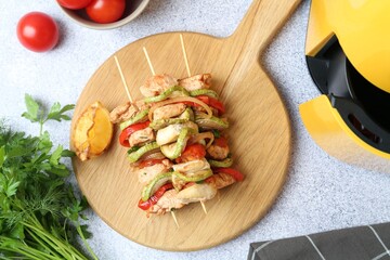 Tasty skewers with chicken, vegetables and air fryer on light table, flat lay