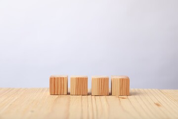 Blank cubes on wooden table against light background, space for text