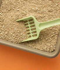 Pet litter tray with a scoop for cleaning with a beige background