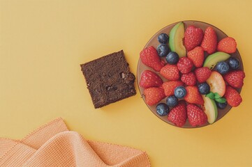 Chocolate brownie and cake garnished with fresh fruits against a bright yellow background
