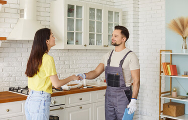 Handshake of plumber and customer at home kitchen, woman greeting professional repairman to repair...
