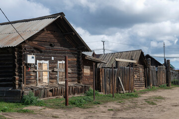 Old wooden houses on a rural street on a cloudy day. Khuzhir, Olkhon Island, Russia