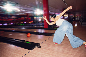 Woman throwing ball while playing bowling at bowling alley