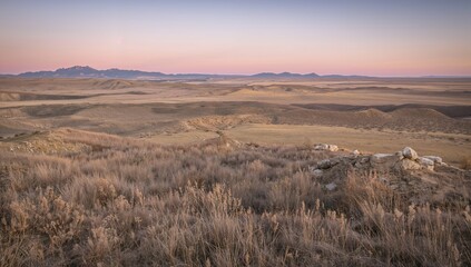 Fototapeta premium Dawn over a rugged terrain of bushes and rolling prairie hills in a remote area
