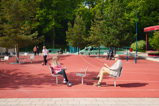 Senior woman and man sitting comfortably on chair in middle of ground at park
