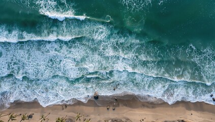 Bird's-eye view of ocean waves hitting the shore, showcasing white foam and crystal-clear blue water.