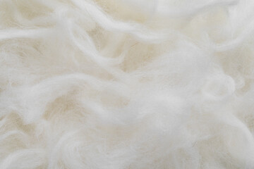 Closeup woolen fiber in neutral white color as background. Natural material texture.