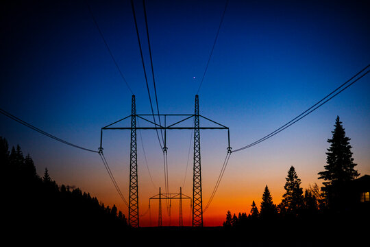 Low angle view of electric pylons against idyllic sky at dusk