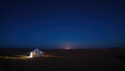 Nighttime desert camp atop a sandy dune beneath a star-filled blue sky.