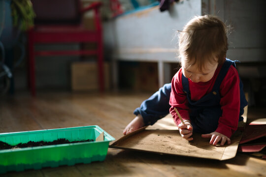 Boy scribbling on pizza boxes while sitting on floor at home