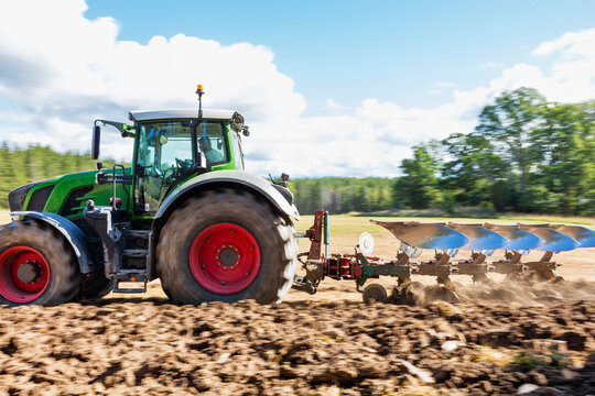 Farmer ploughing field with tractor at sunny day