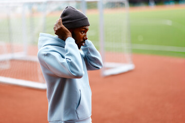 Athlete adjusting beanie on sports field before training