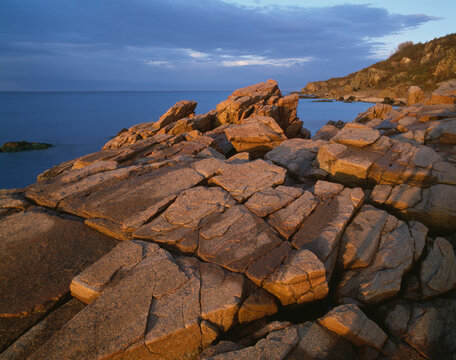 Rock formations by sea at sunset