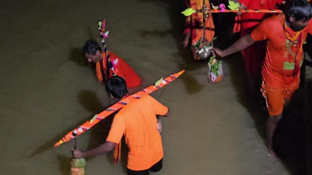 Authentic overhead footage of Kanwariya devotees collecting holy water during the sacred Kanwar Yatra at night in India. Wearing traditional saffron attire and carrying decorated Kanwars Kawads