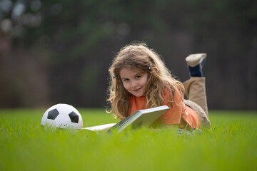 Kid reading a book in the grass. Kid read a book story outdoors. Kid reading book in the meadow on...