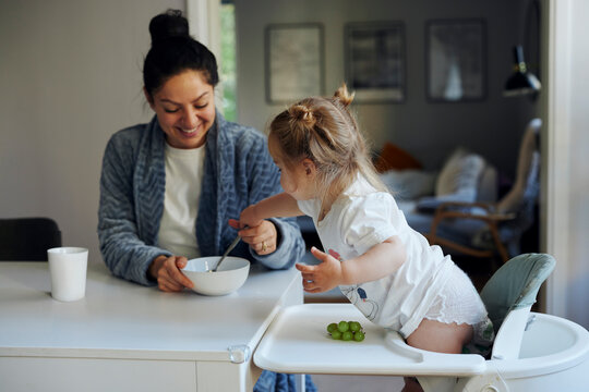 Mother and daughter spending leisure time while having breakfast at home