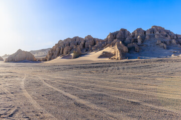 Desert road and tire tracks with Yardang landform mountain scenery in Xinjiang, China.