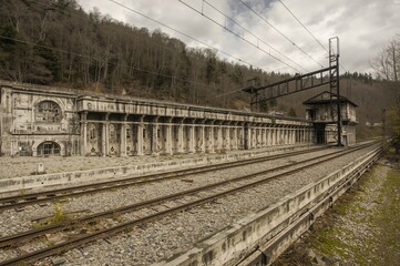 Obraz premium Deserted quarry adjacent to a disused railway track with decaying industrial structures and buildings