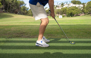 Side view of a young sport man legs playing golf at the golf course.